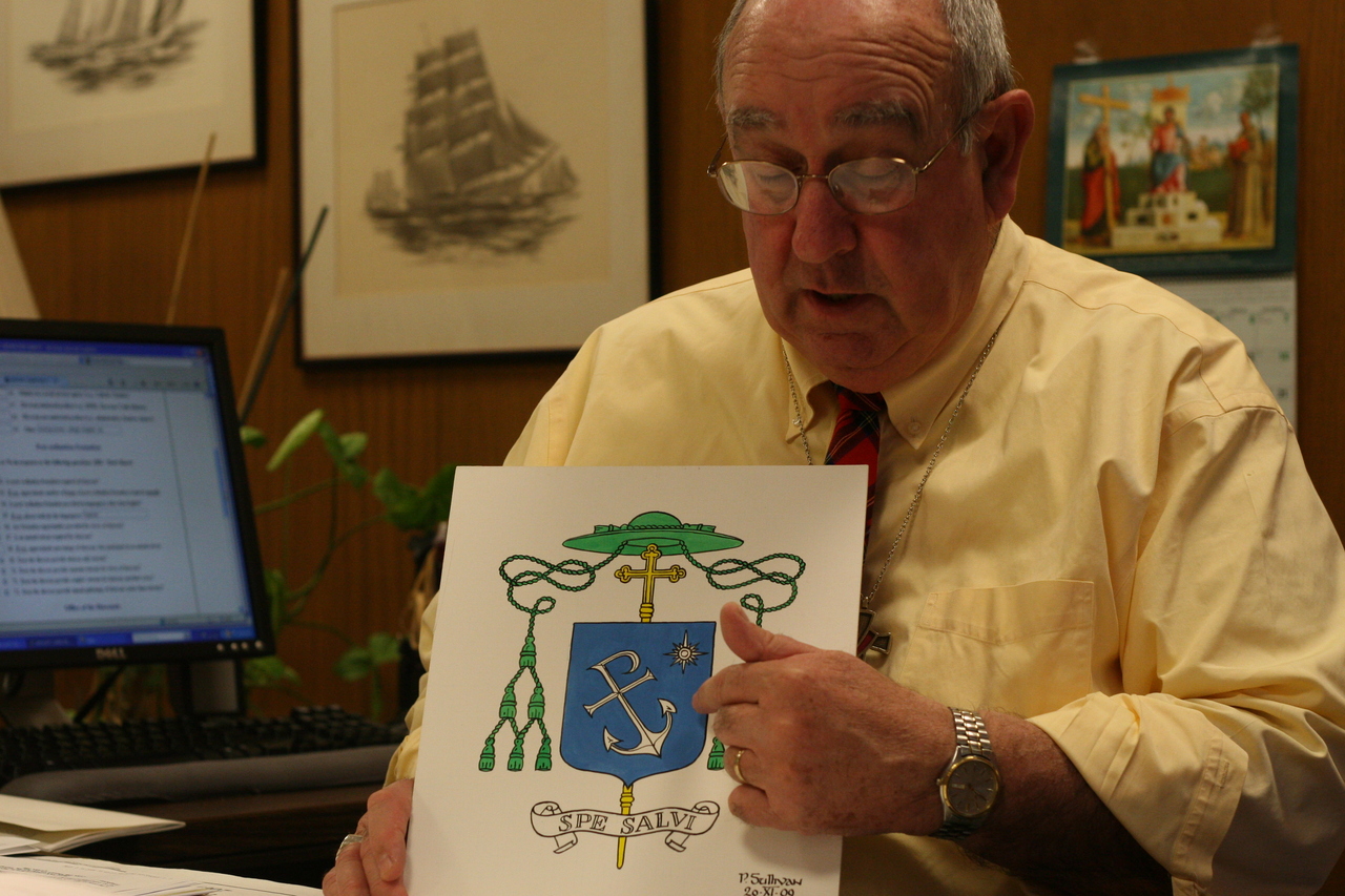 THE DESIGN: Deacon Paul Sullivan displays the design for the achievement that will serve as Auxiliary Bishop Robert C. Evans’ coat of arms.