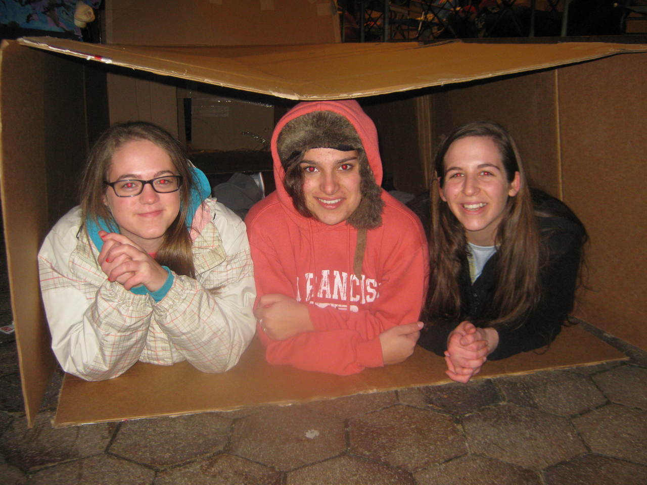 HUDDLED TOGETHER: From left to right, Prout School, Wakefield students Sarah Iselin, Chandler Dupre and Tory Kern see what it is like to sleep in a cardboard box as they prepare to spend the night on the grounds of the Cathedral of SS. Peter and Paul, Providence for the ‘Sleep Out.’ The event offered the students a closer look at issues of homelessness.