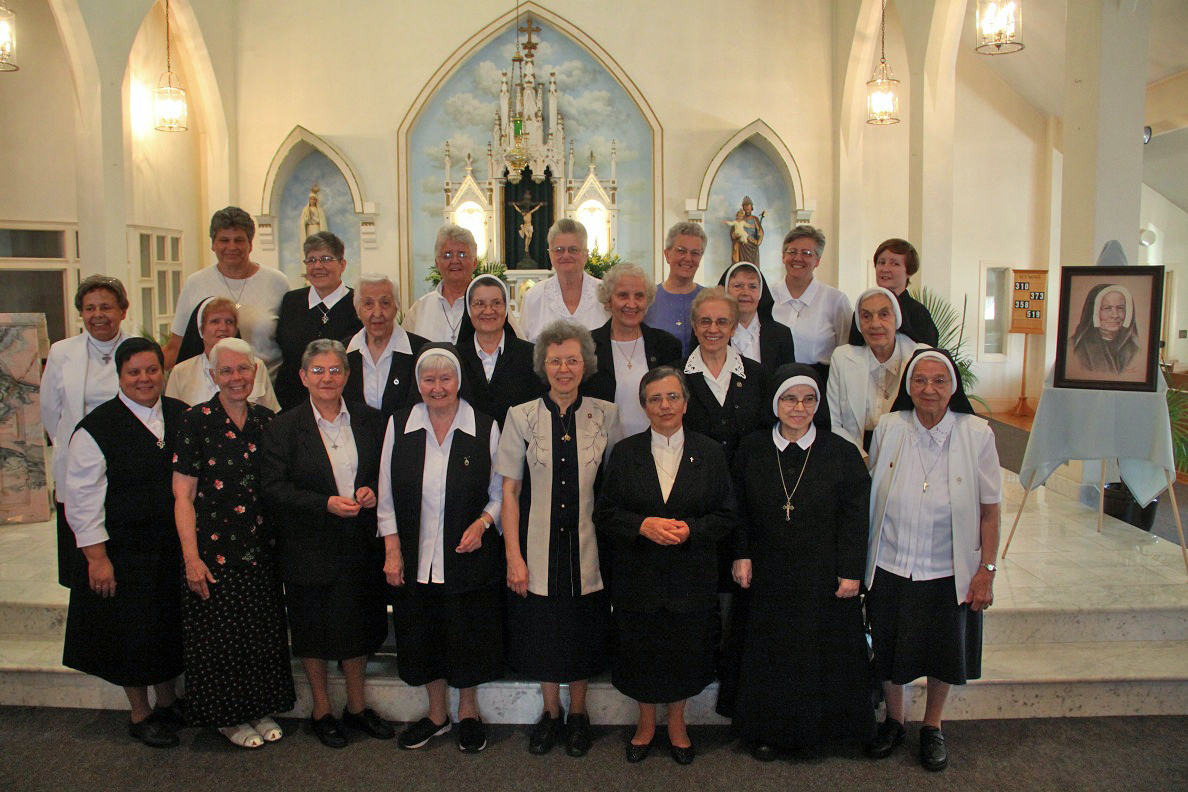 REMEMBERING THEIR FOUNDRESS: A group of Sisters of St. Dorothy gathers in front of the altar at St. Elizabeth Church, Bristol following their anniversary Mass to pay tribute to Saint Paula Frassinetti, foundress of their order. The sisters established themselves in Rhode Island in 1911 at Holy Rosary Parish, Providence for the purpose of ministering to the Portuguese immigrant community. The Dorotheans also responded to many calls to serve at a number of locations in the area through the years, including the staffing of new schools at St. Francis Xavier Parish in East Providence in 1939, and at Jesus Saviour Parish, Newport, in 1957. In 1960, the sisters purchased property on Mt. Hope Bay in Bristol for a formation house, which now serves as the order’s provincial house. In 1964, the Sisters of St. Dorothy opened Our Lady of Fatima High School in Warren.