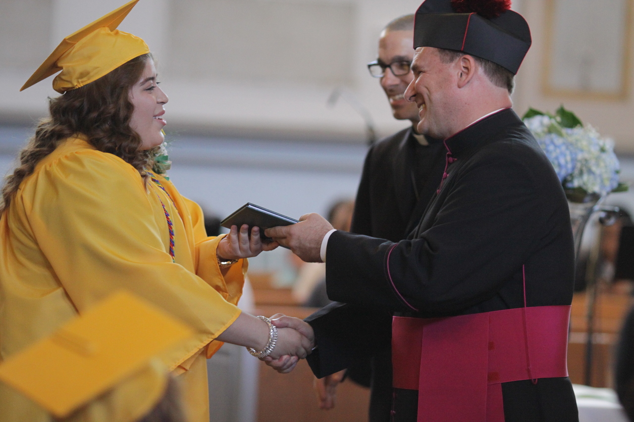 Aida M. Buccio, who will attend Community College of Rhode Island, receives her diploma from Msgr. Albert A. Kenney, diocesan Vicar General and Moderator of the Curia, as Father James Ruggieri, pastor of St. Patrick Parish, looks on.