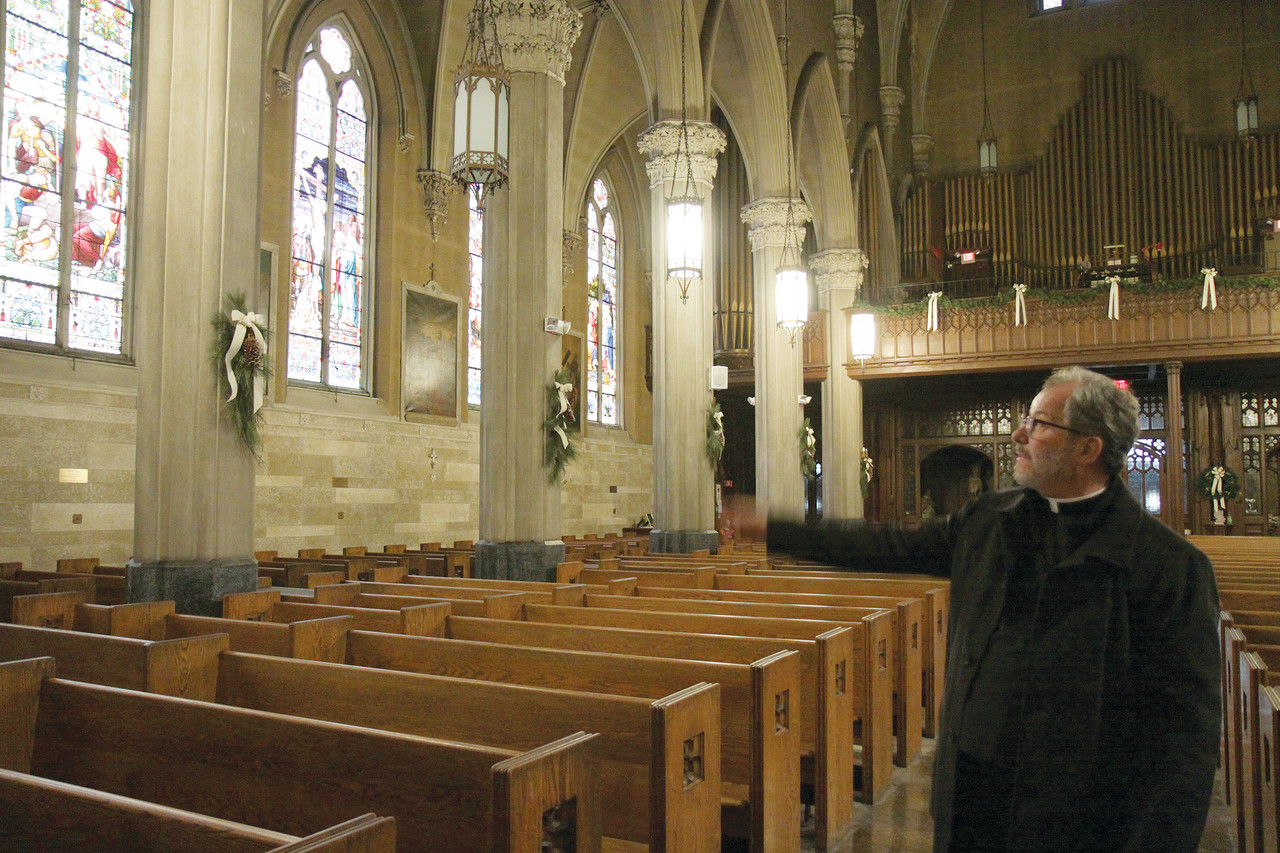 Preserving history: Msgr. Jacques Plante, pastor of the Church of St. Mary, points to the restoration work planned for the Providence church’s stained glass windows thanks to a $50,000 grant it has been awarded.