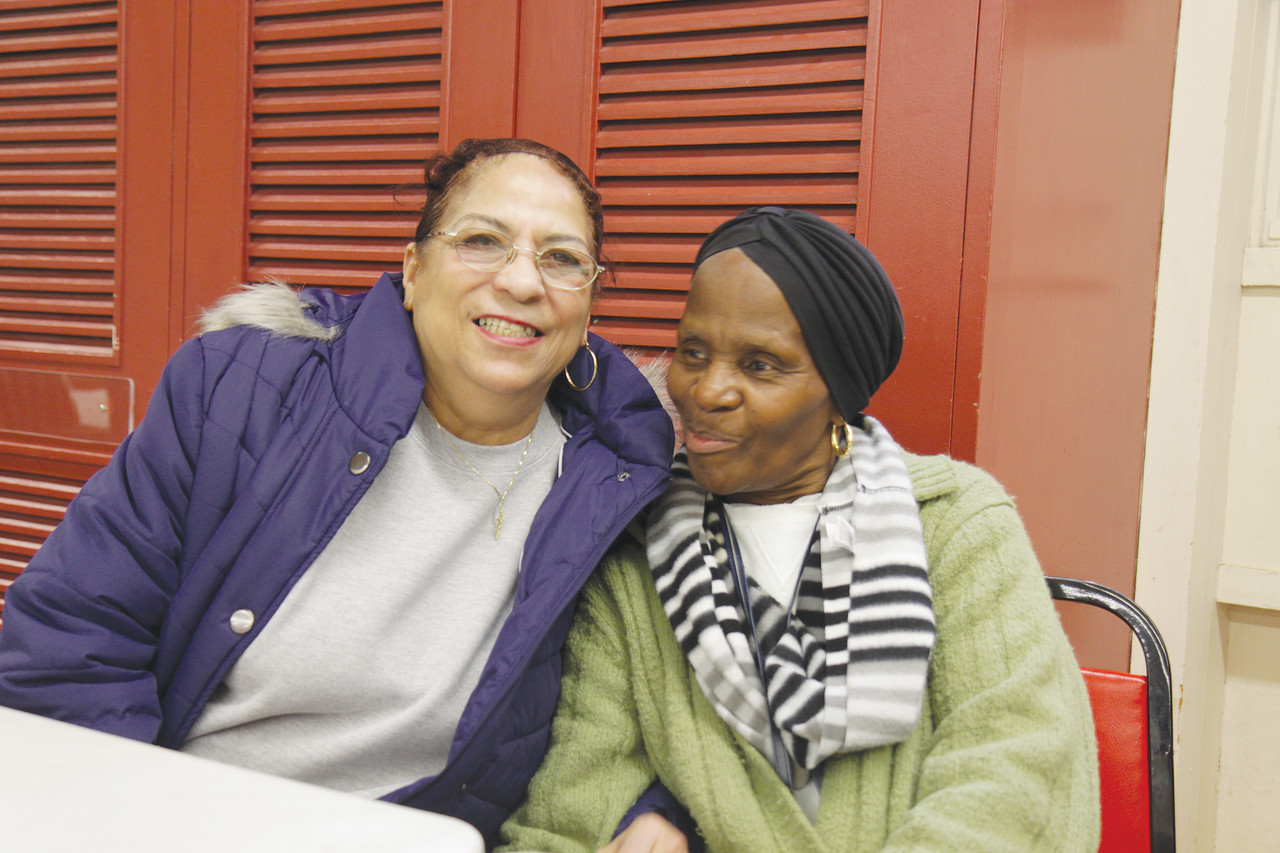 FAMILY LIVING: Shirley Brame and Lorraine DeCosta share a laugh over lunch at the St. Martin de Porres Center. “This is a friendly place. Everybody’s treated like family here,” said DeCosta.