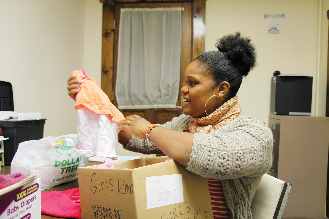 MEETING THE NEED: Dulcelina Landim searches through a box of donated clothing for an outfit for her one-year-old daughter. The mother of two receives regular donations of diapers and other essential items from St. Gabriel’s Call at the Project Hope outreach center in Pawtucket. To donate to the CCA, visit https://providencediocese.thankyou4caring.org