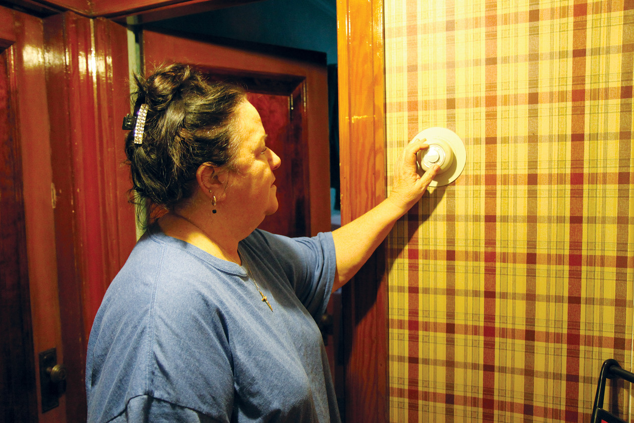 CONSERVING ENERGY: Angelique Velsor adjusts the thermostat in her Woonsocket home. With help from Keep the Heat On, she says the family should have enough heating oil in the tank to get them through the remaining winter months.