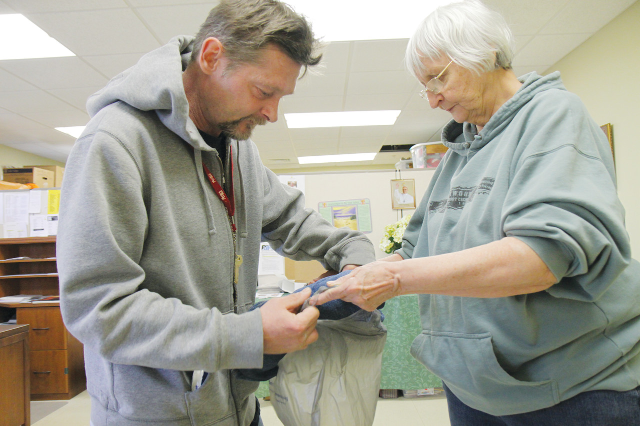 CHARITABLE HEARTS: Volunteer Francine Fontaine assists Tony Brice, a regular client, with a bag of clothing at the Kent County satellite office.
