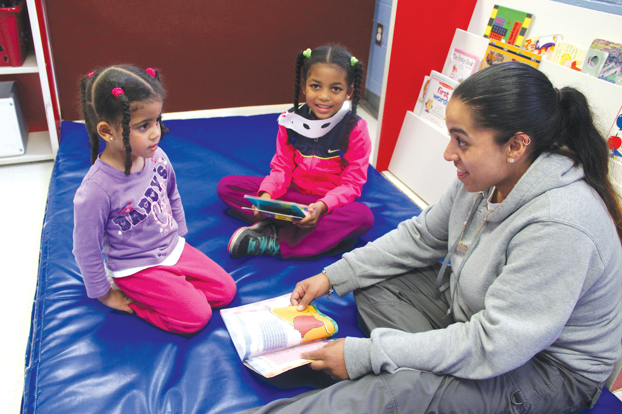 CARING FOR FAMILIES: Tatyana Mendez, teacher’s assistant at Washington Park Child Care Center in Providence, reads to Gialeah, 2, and Giandeliz, 5. These children are able to attend Washington Park thanks to donations to the Cabrini Fund, which helps pay part of the cost of licensed child care for low or modest income working families.