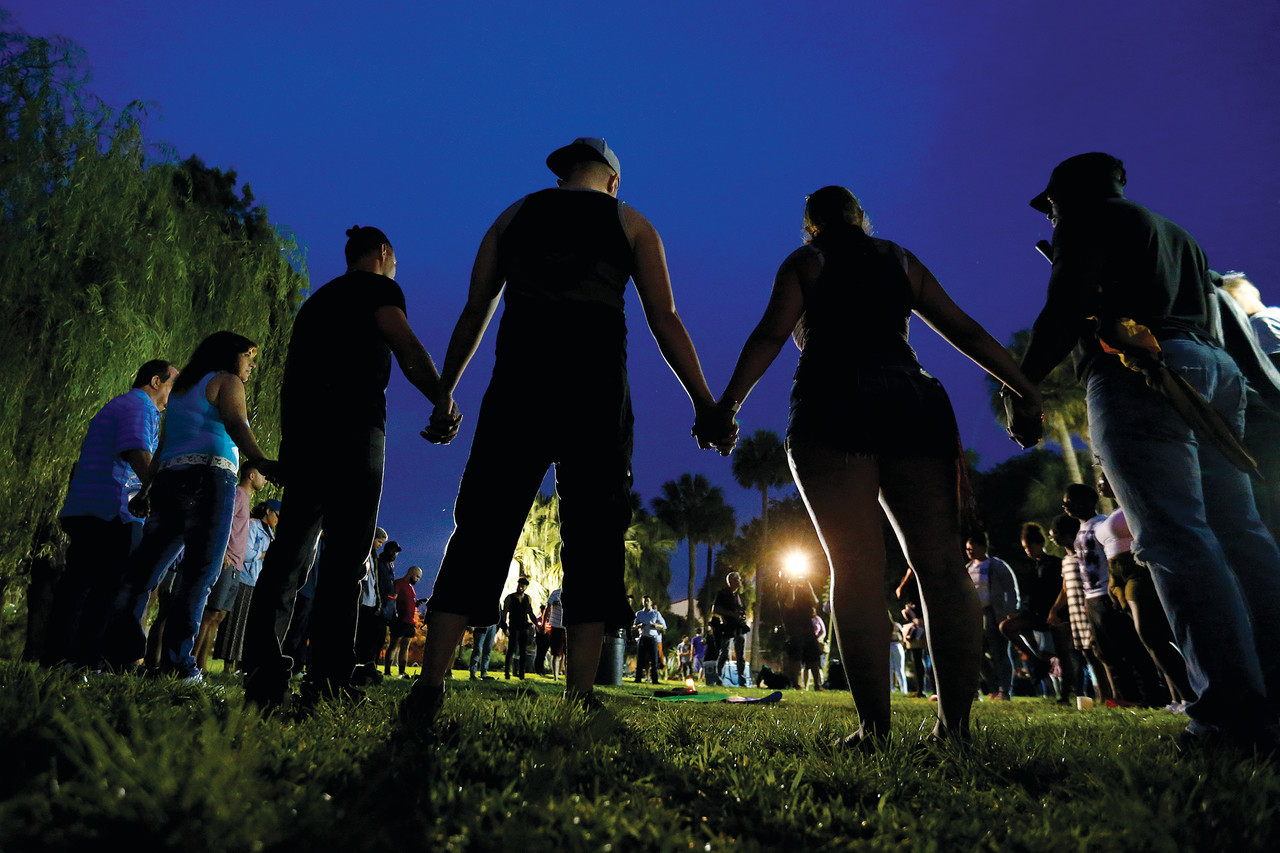 People hold hands in a circle during a June 12 vigil in an Orlando, Fla., park following a mass shooting at the Pulse nightclub in that city earlier that morning.