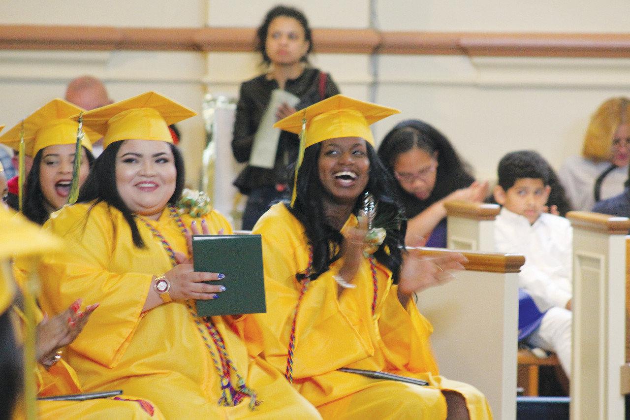 Jenifer Maida and Brooxana Pierre cheer as their classmates receive their diplomas.