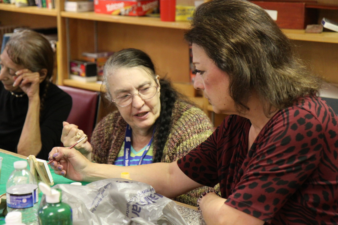 A staff member assists a participant with an activity at Fruit Hill Day Services for the Elderly.
