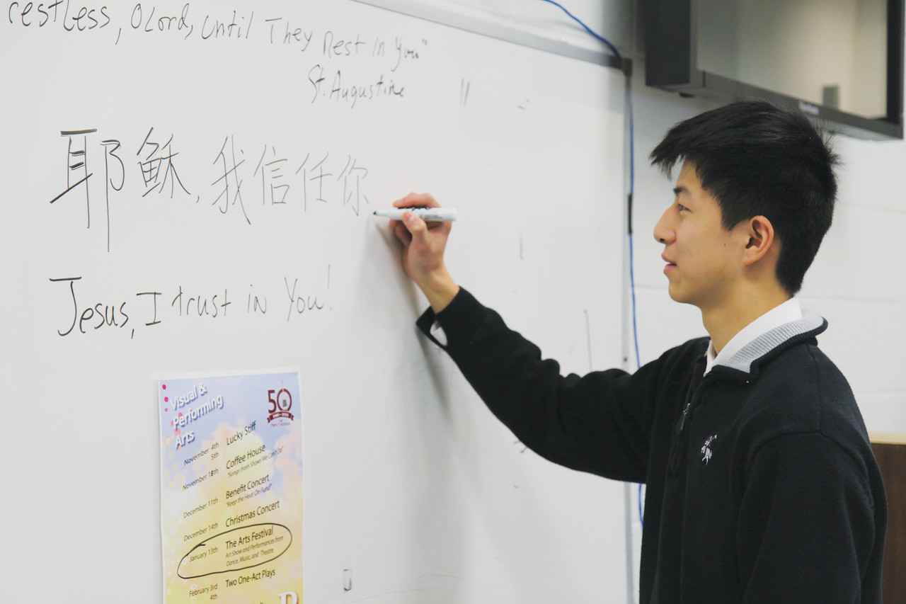 Yifan “Louis” Niu, a sophomore at The Prout School from China, has helped his religion teacher develop Mandarin translations for several important Catholic sayings. Here, he translates the prayer of St. Faustina, “Jesus, I trust in you.”