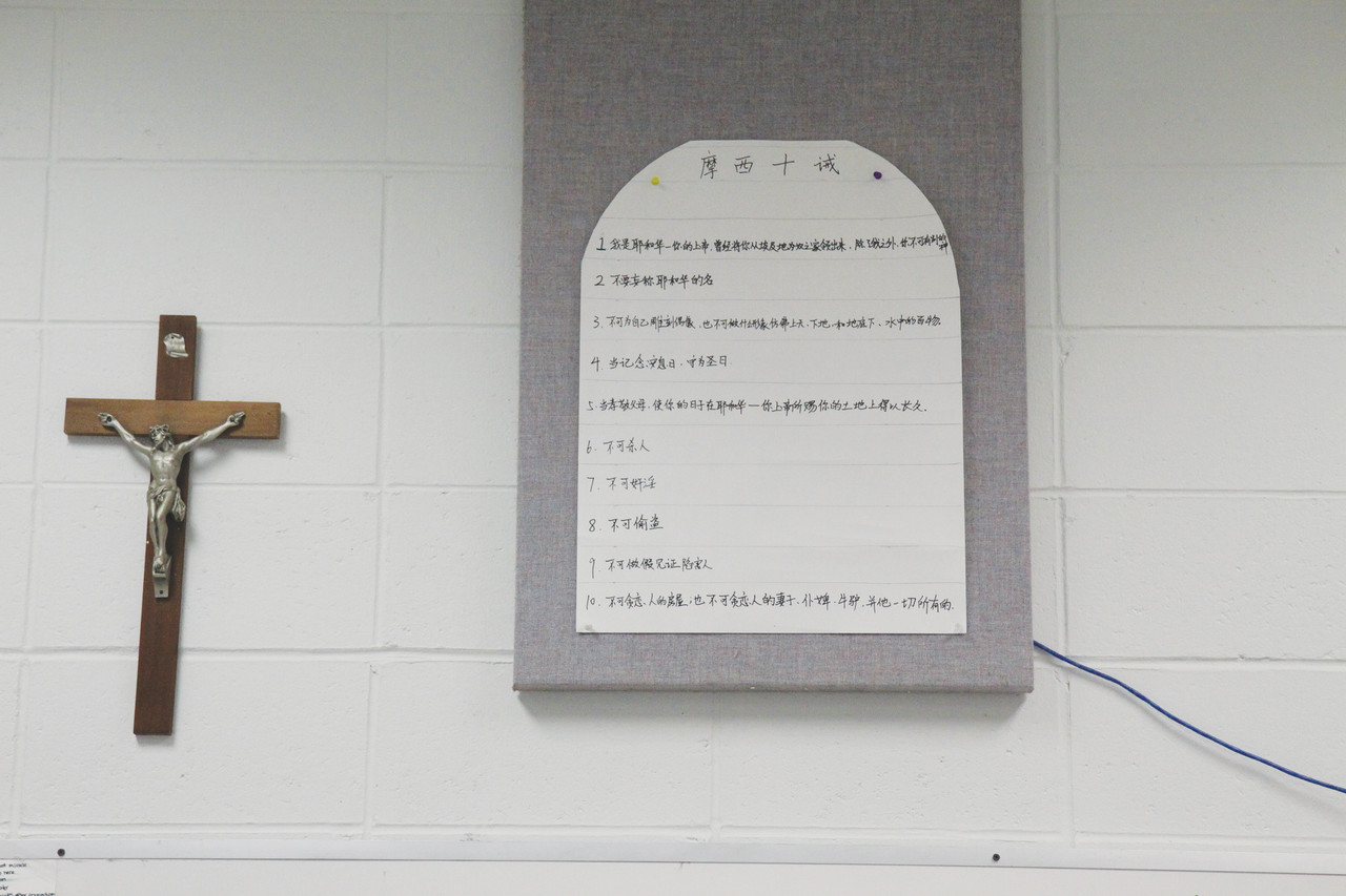 A Mandarin translation of the 10 commandments hangs beside a crucifix in a religion classroom at The Prout School.