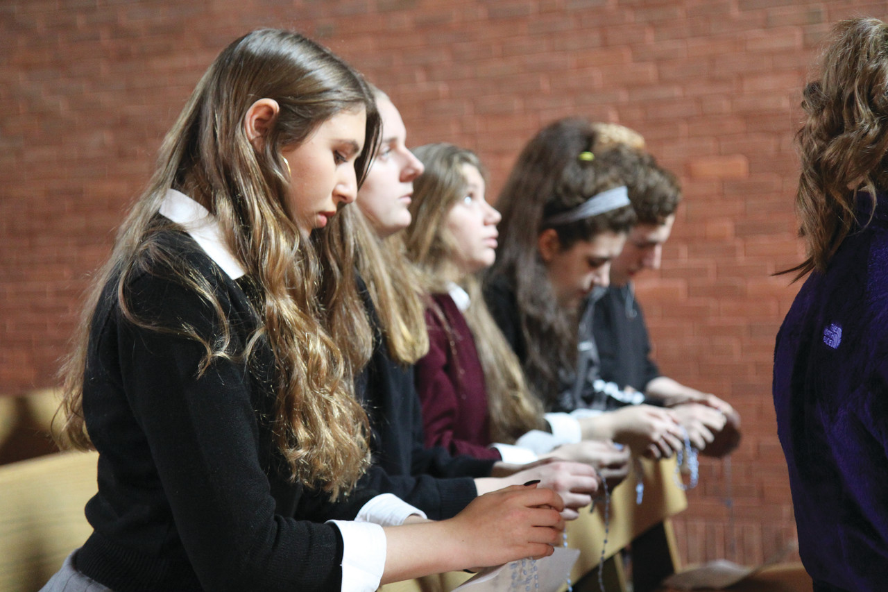 HOLY PILGRIMAGE: Trinity DiNunzio, far left, joins her classmates in praying the rosary at Immaculate Conception Church, Cranston. Students from The Prout School recently embarked on a daylong pilgrimage to commemorate the Marian Year, visiting parishes throughout the diocese that feature different names for the mother of Christ.