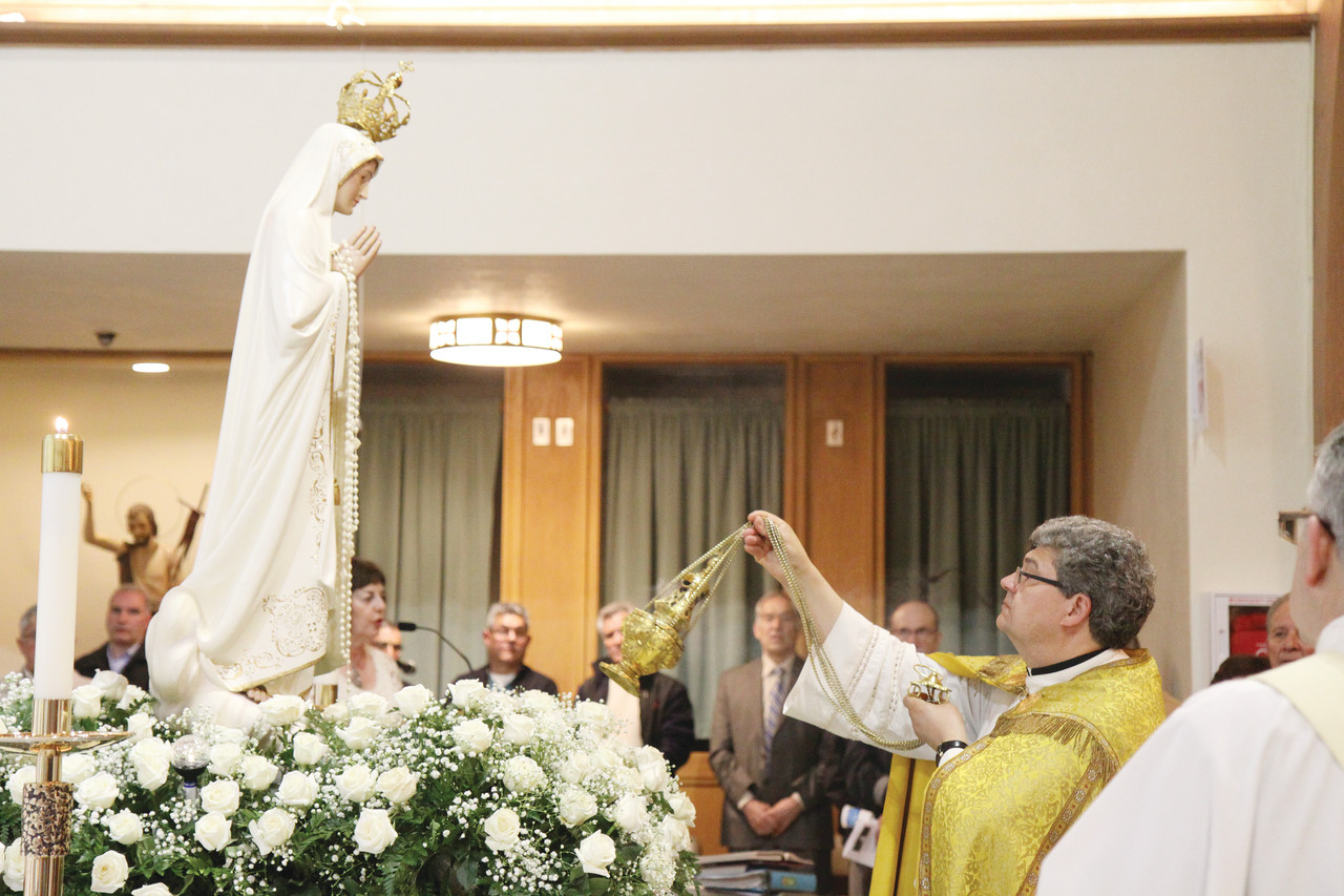 Pastor Father Fernando Cabral incenses a statue of the Blessed Mother following a procession at Our Lady of Fatima Church, Cumberland, on Saturday evening.