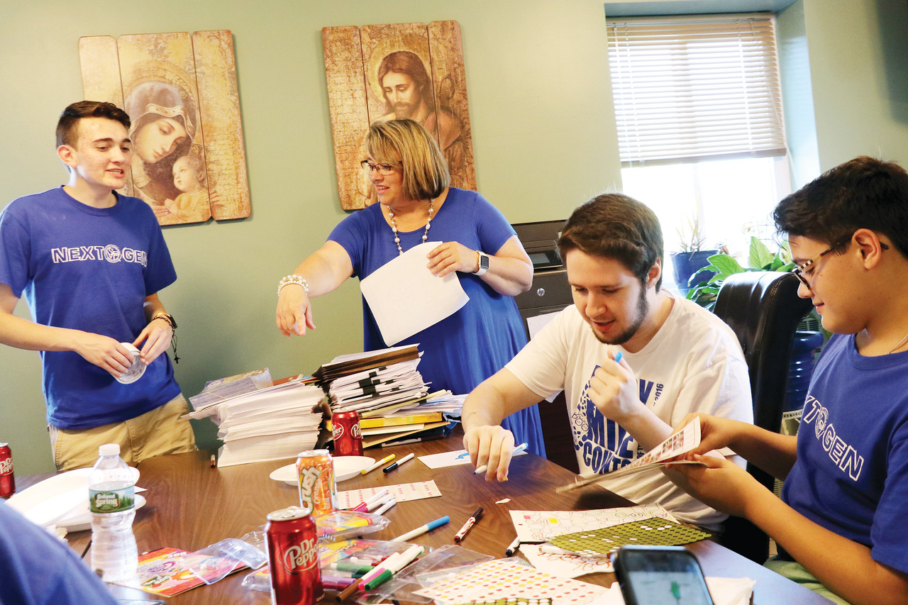 Renee Brissette assists some of her Next Gen students Sunday in writing message cards to inspire those in need.