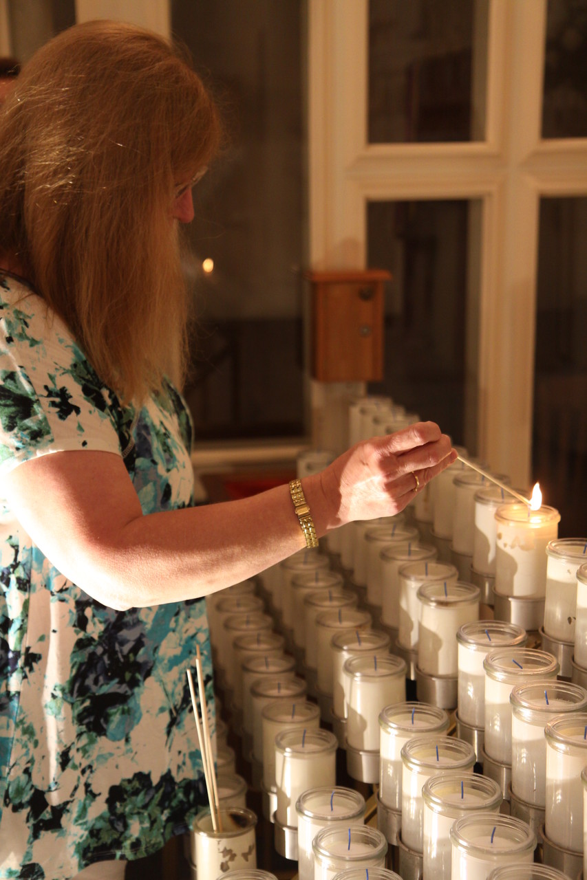 Deb Arruda, a parishioner at Our Lady of Mount Carmel Parish, Bristol, lights a candle in front of a statue of Our Lady of Fatima following the holy hour.