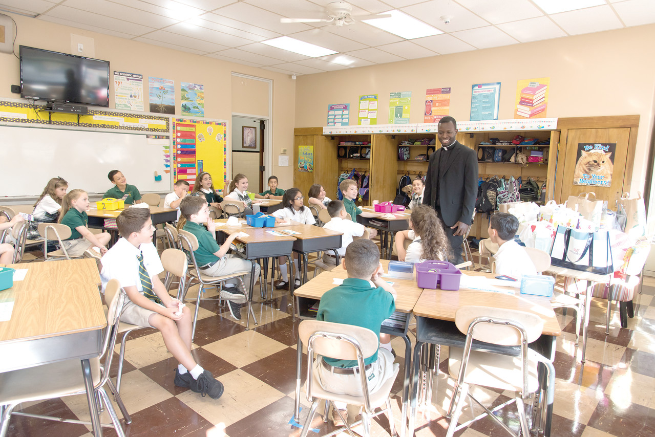 Newly ordained Father Jean Joseph Brice visits the third grade classroom at Saint Augustine School on their first day back to class on August 28. Father Brice is serving as Assistant Pastor of Saint Augustine Parish in Providence.