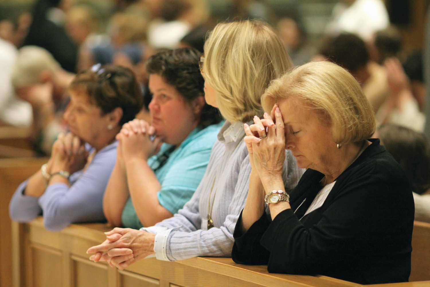 Women kneel in prayer during Mass at the Cathedral of Saints Peter and Paul, Providence.
