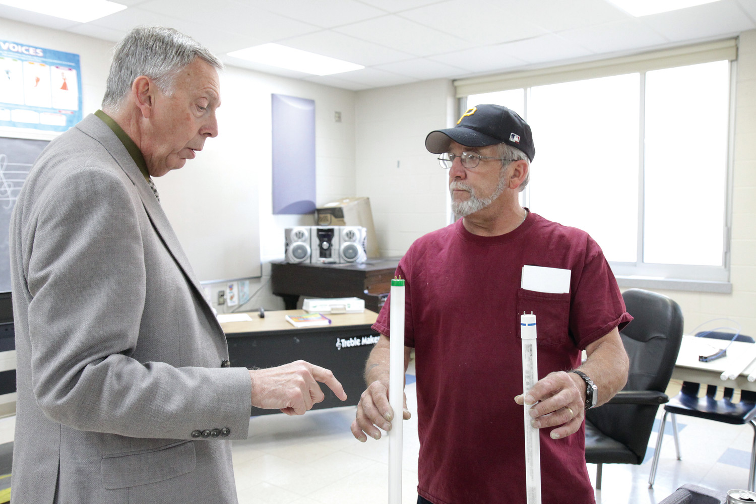 John Dickinson, right, an electrician with Superior Electric Company, demonstrates to Principal Dr. Arthur Lisi the difference between LED and traditional fluorescent school lighting. According to an energy audit conducted by RISE Engineering, the new lighting will save the school approximately $8,000 per year.
