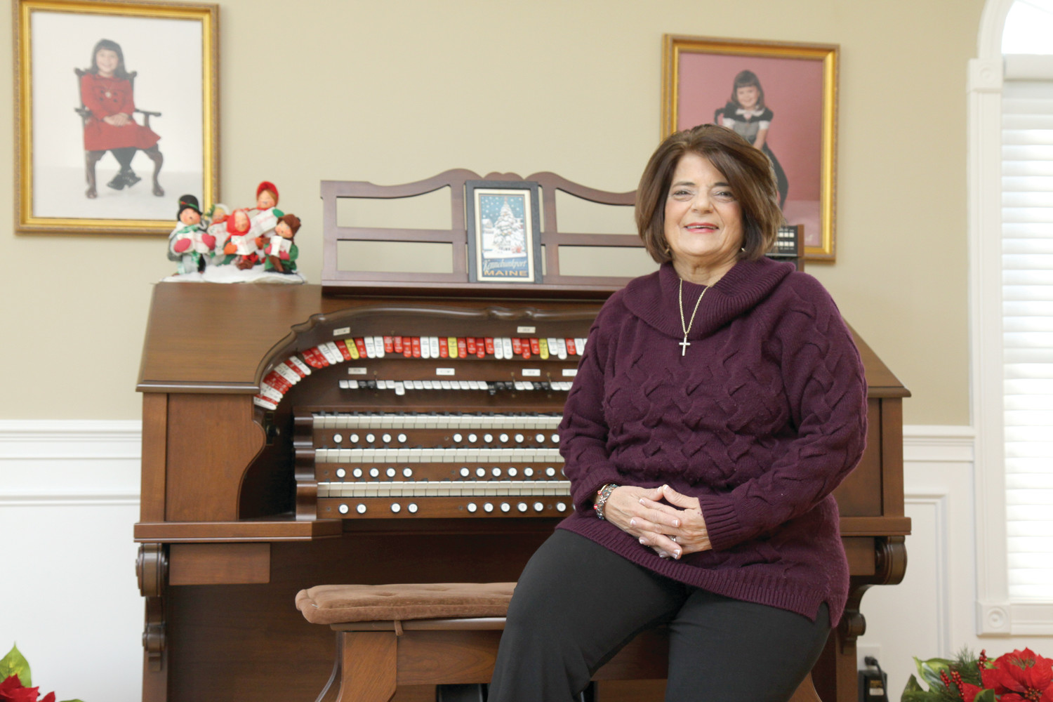 Carol Mitola, a gifted musician, sits beside her organ at her Scituate home with photos of her daughters Kara, who graduated from St. Mary Academy Bay-View, and Marissa, a La Salle grad, displayed on the wall behind her. Mitola has chronic kidney disease and is hoping a living kidney donor will help her restore her health before she needs to go on dialysis.