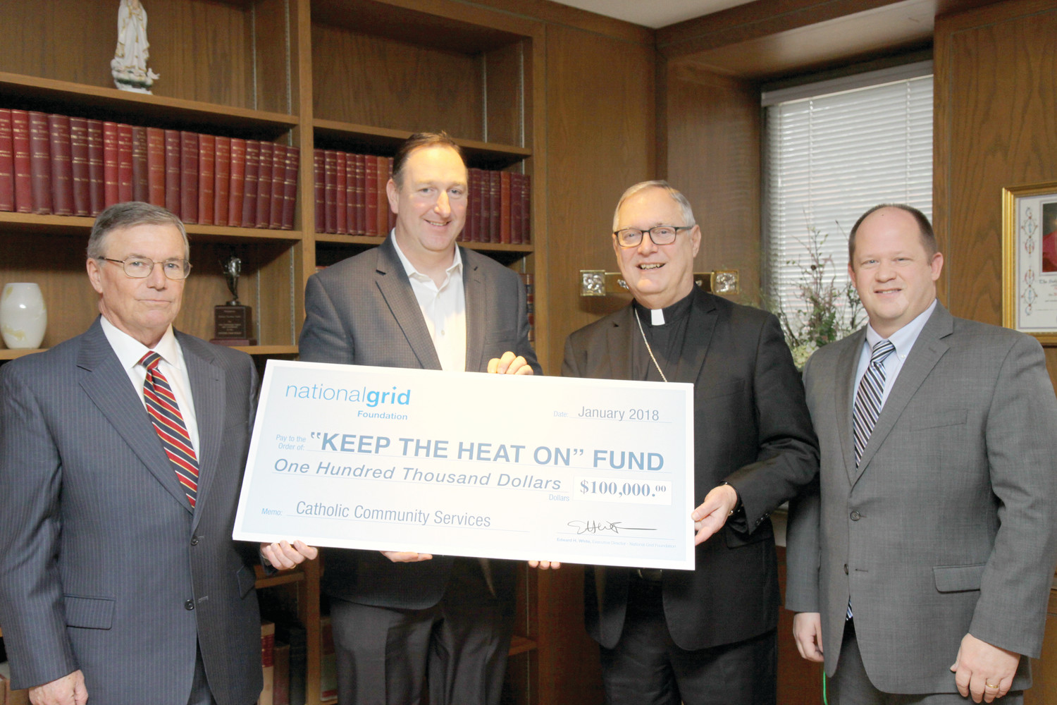 From left, Michael Ryan, director of government affairs for National Grid Rhode Island, and Ed White, executive director of the National Grid Foundation, present Bishop Thomas J. Tobin and James Jahnz, emergency assistance network coordinator for the diocese, with a $100,000 donation to the “Keep the Heat On” program.