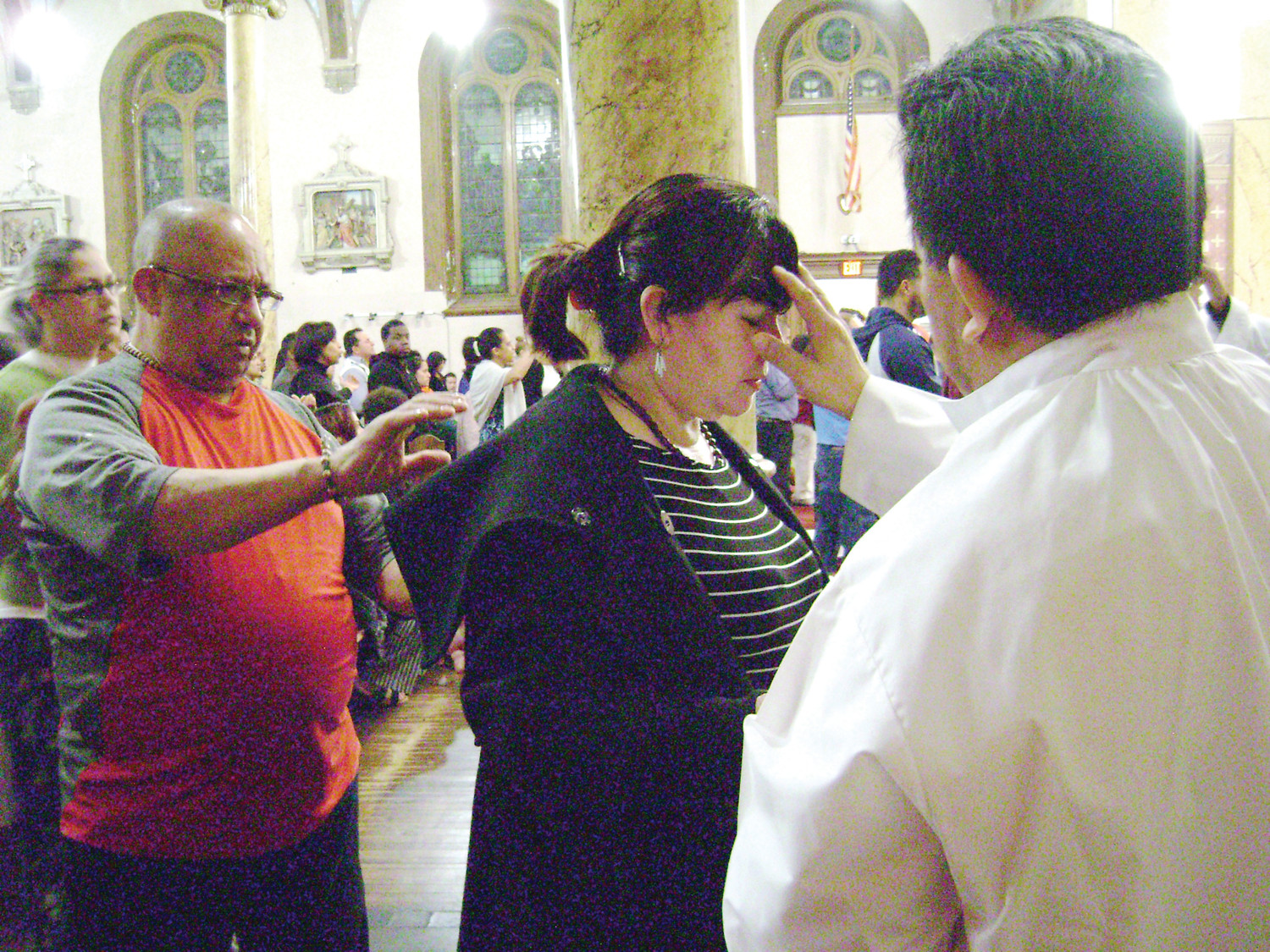 Miguel Soto, right, prays over a person for healing while Mario Orellana stands ready to catch the person if she “rests in the Spirit” at St. Charles Church’s Spanish-language healing Mass on Tuesday, April 24.