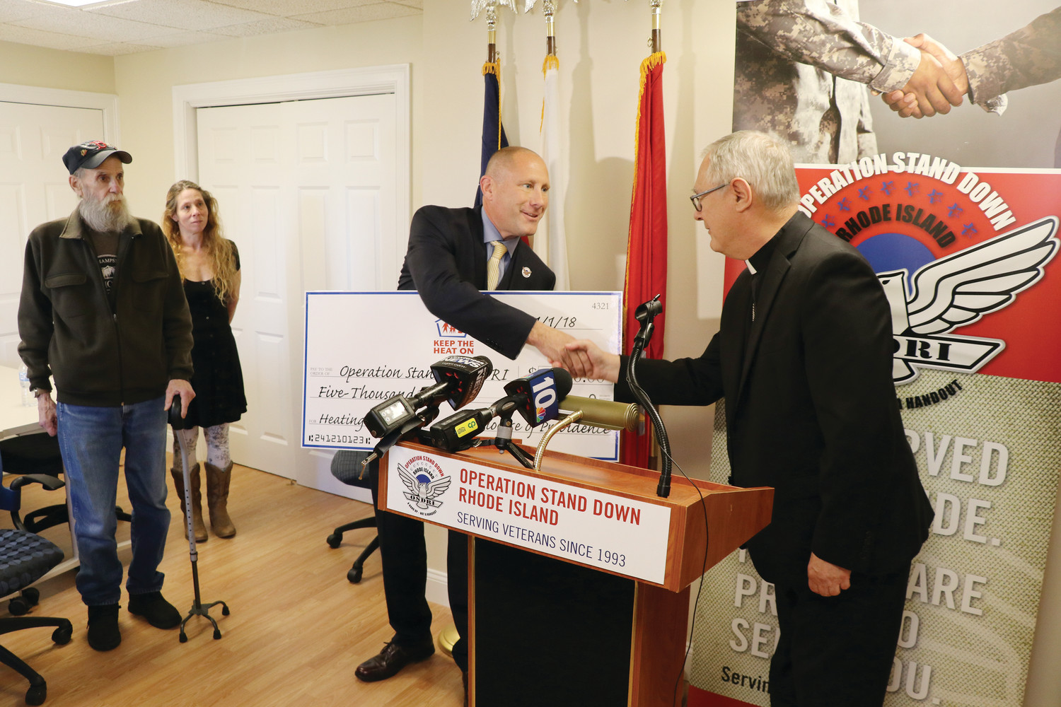 Bishop Thomas J. Tobin presents a donation for $5,000 from ‘Keep the Heat On’ to Erik B. Wallin, Captain USAF (Fmr.), executive director and general counsel for Operation Stand Down RI, to help the organization provide heating assistance to veterans in need.