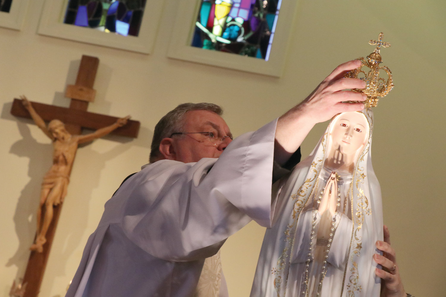 Father David Green, pastor of St. Martha Parish in East Providence, places a crown atop a statue of Our Lady of Fatima during the special day of renewal.