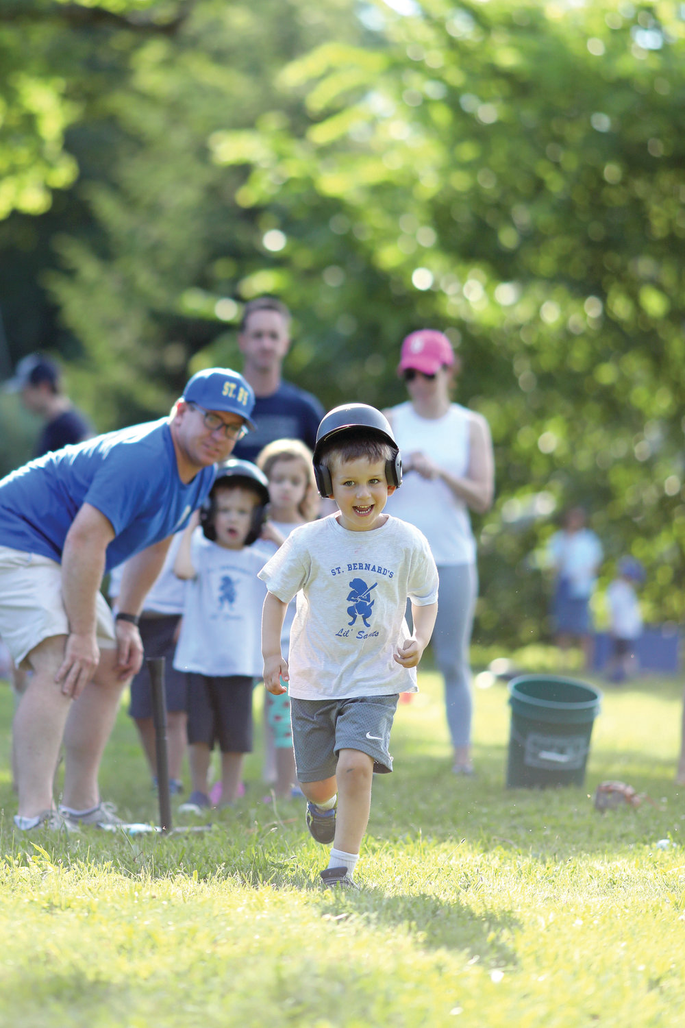 Coach Ed Cooney, a parishioner at St. Bernard Church in North Kingstown, helps 3 to 6-year-old “Lil Saints” learn the basics of baseball at St. Bernard’s tee-ball program which ran throughout June.