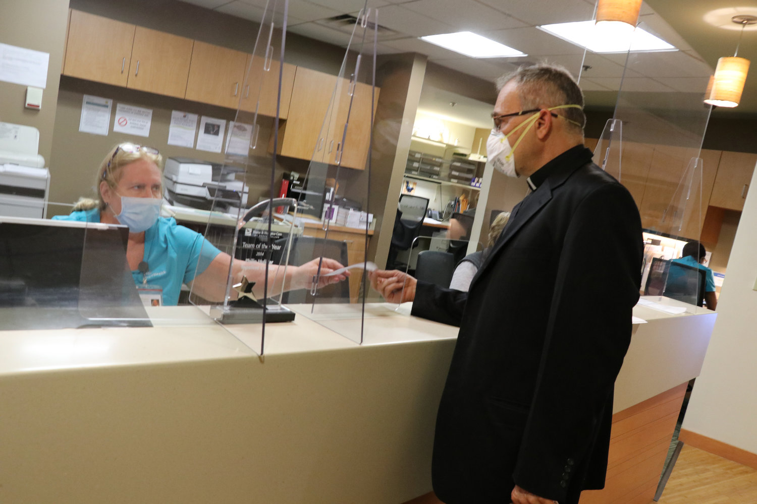 Father Albert Ranallo, coordinator for Pastoral Care for Health Facilities in the Diocese of Providence, gets an update on the status of patients he is there to provide the Sacrament of the Sick to.