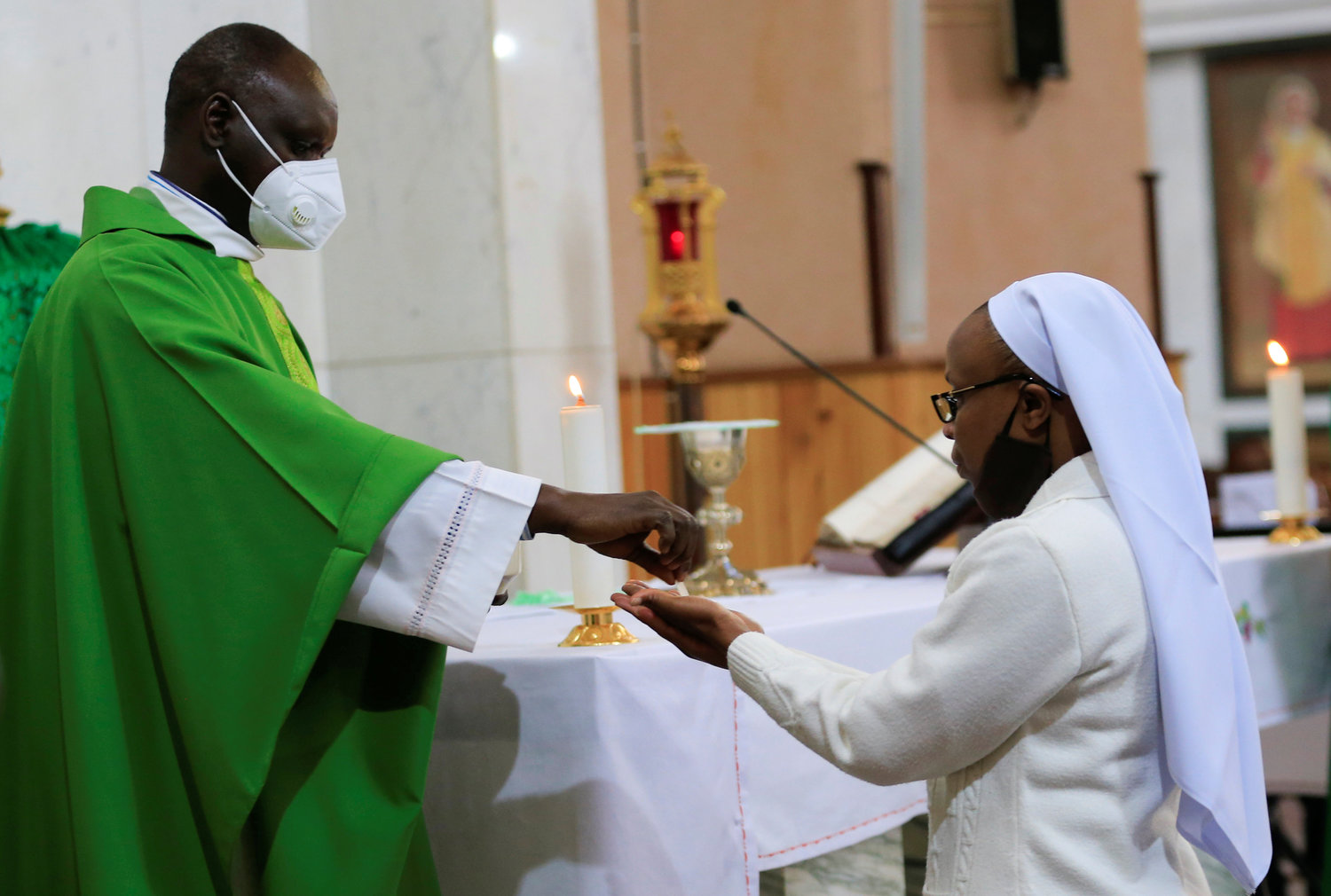 A priest wearing a face mask gives Communion to a woman religious during a July 19, 2020, Mass at the Cathedral Basilica of the Holy Family in Nairobi, Kenya, on the first day the government allowed churches to reopen for worship during the coronavirus pandemic. The Vatican issued a new instruction July 20 on pastoral care that emphasizes the role of lay men and women in the church's mission, but said most parishes must be led by priests.