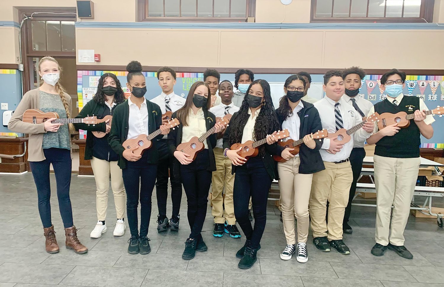 The seventh grade class from McVinney School in Providence smiles while holding their new ukuleles that were recently donated to the school on behalf of McVinney Auditorium, an agency of the Diocese of Providence. The school expressed their gratitude for this donation to their music program.