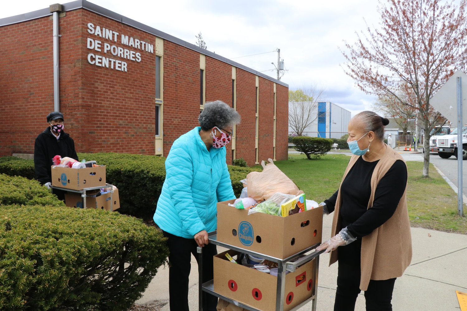 In 2020, Linda A’Vant-Deishinni, director of the St. Martin de Porres Center, right, helps volunteers Cheryl Gray, left, and Gail Harris move boxes of food for distribution to homebound seniors in the midst of the Covid-19 pandemic.