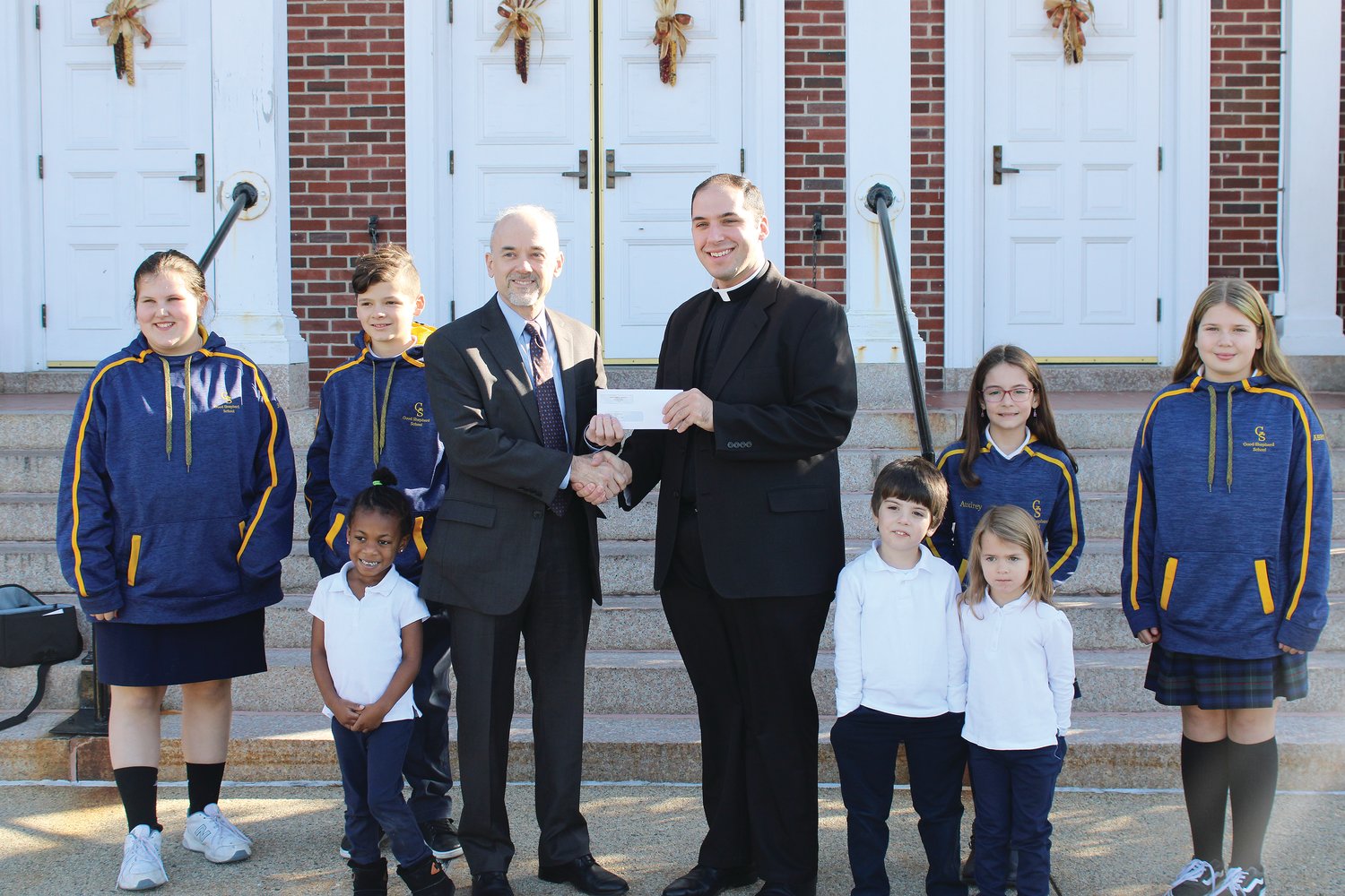Father Ryan Simas, pastor of St. Joseph’s Parish, presents Mayor Dan Gendron with a donation of $25,000 for the construction of a new splash park in Woonsocket, on Tuesday, Nov. 29.