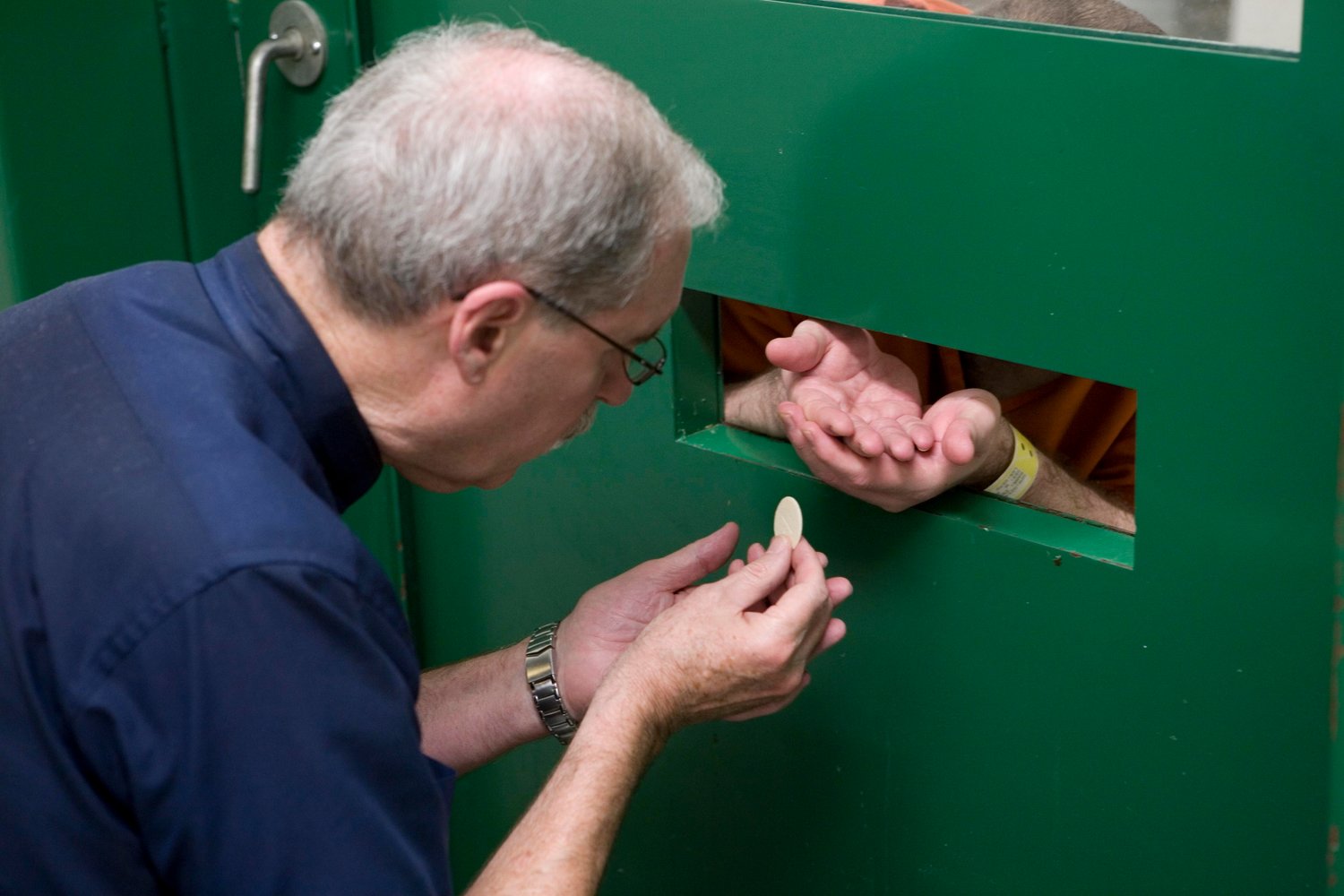 Father Ron Cloutier gives Communion through a slot to an inmate in solitary confinement at a Texas Department of Criminal Justice prison in this undated photo.
