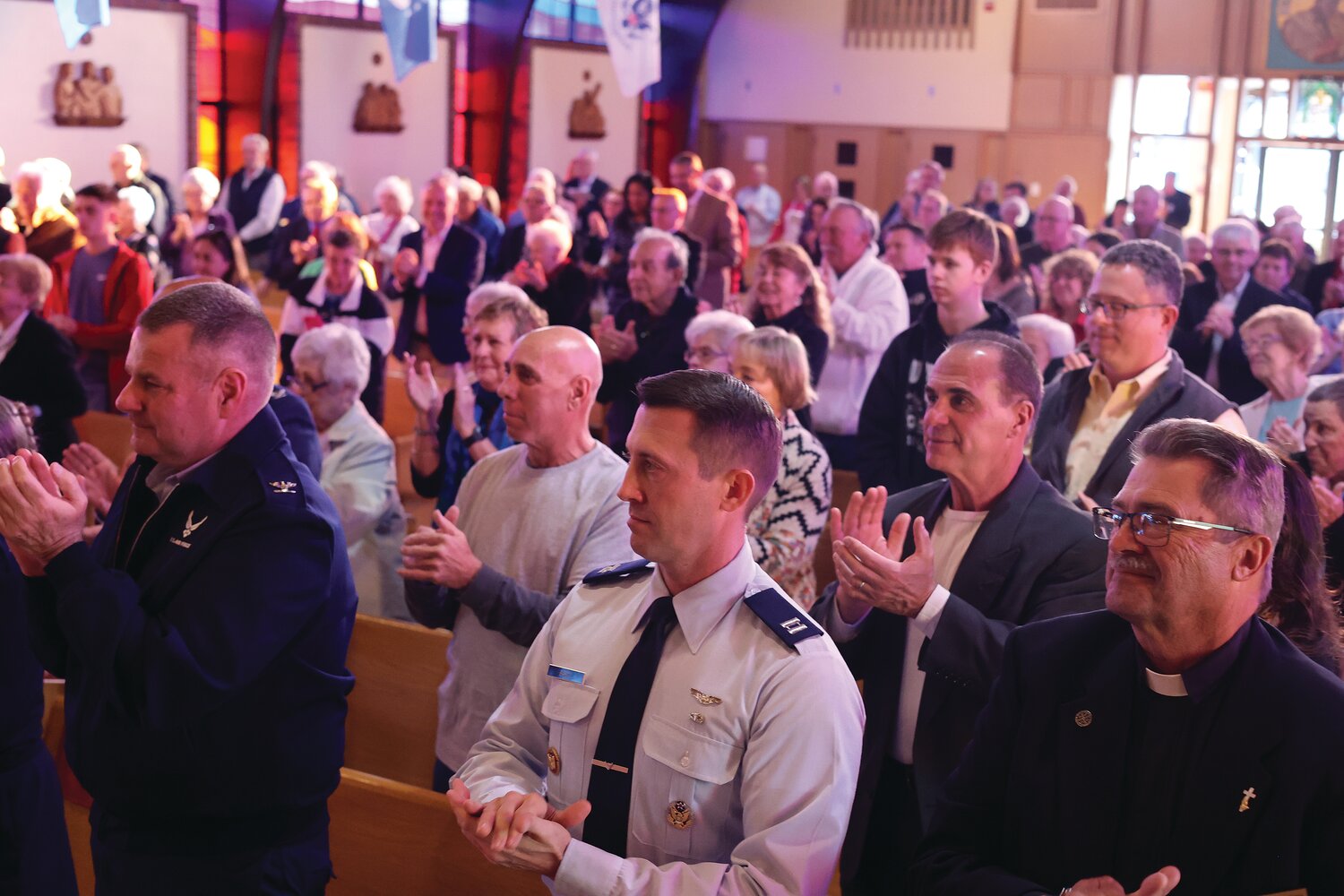 Many members of the R.I. Air National Guard leadership, as well as Father Thurber’s family, friends and parishioners applaud at St. Barnabas after he takes the oath of office.