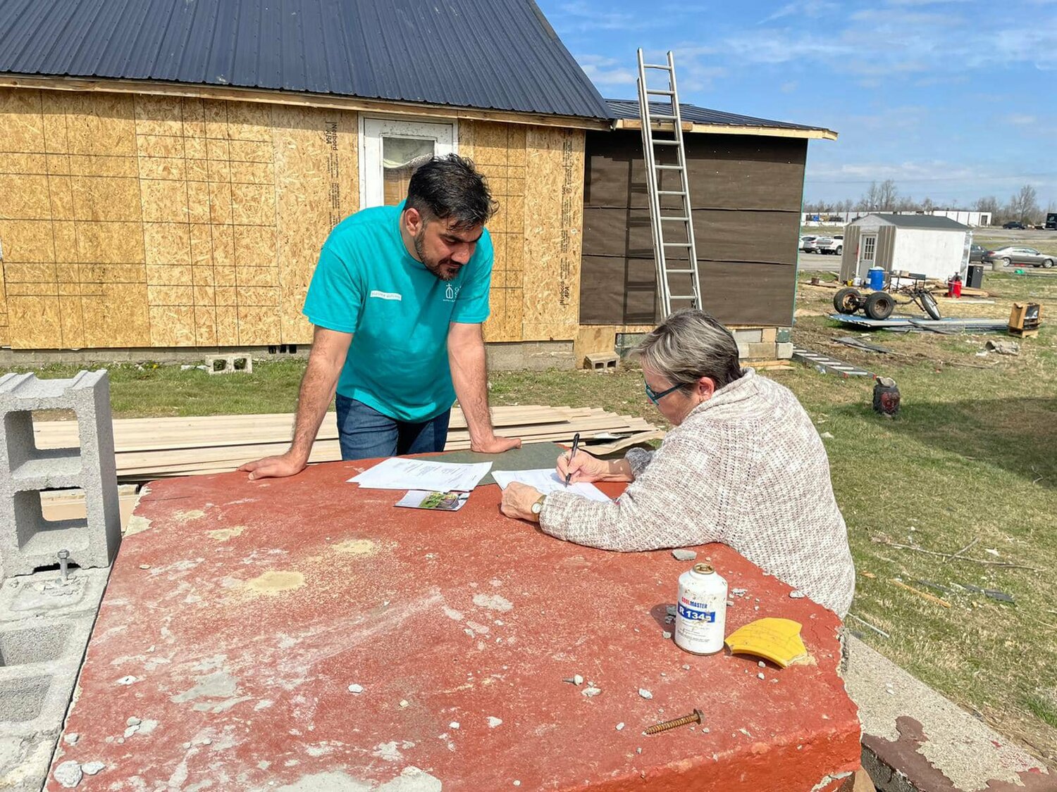 Khaibar Shafaq, a paralegal and case manager for Catholic Charities of the Diocese of Owensboro, Ky., works with Sheila Rose at the construction site of her home rebuild in Dawson Springs, Ky., March 15, 2022. Rose's home was completely destroyed by a tornado Dec. 10, 2021.